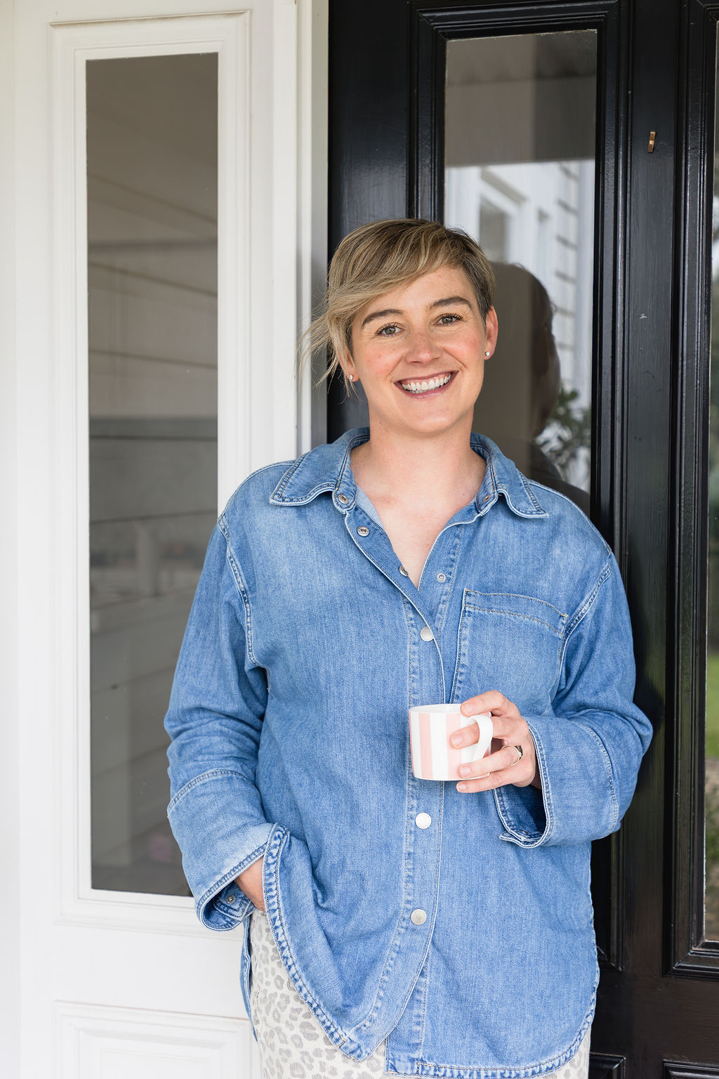 Dominie, business coach and consultant, smiling in a doorway with a mug
